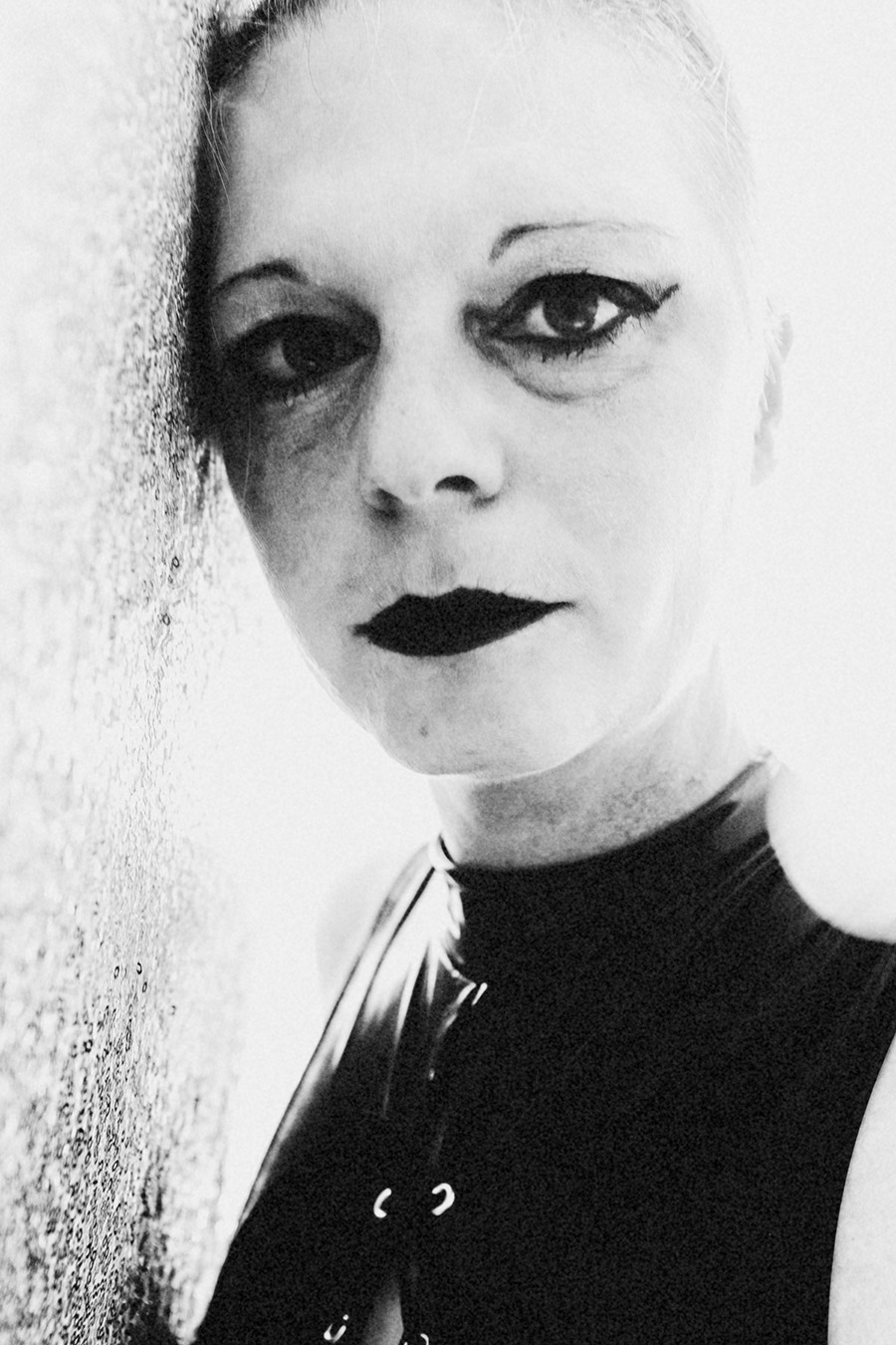 Frau im Latexanzug, um sie gewickelt ein Band mit der Aufschrift "Danger" fotografiert in schwarz/weiss