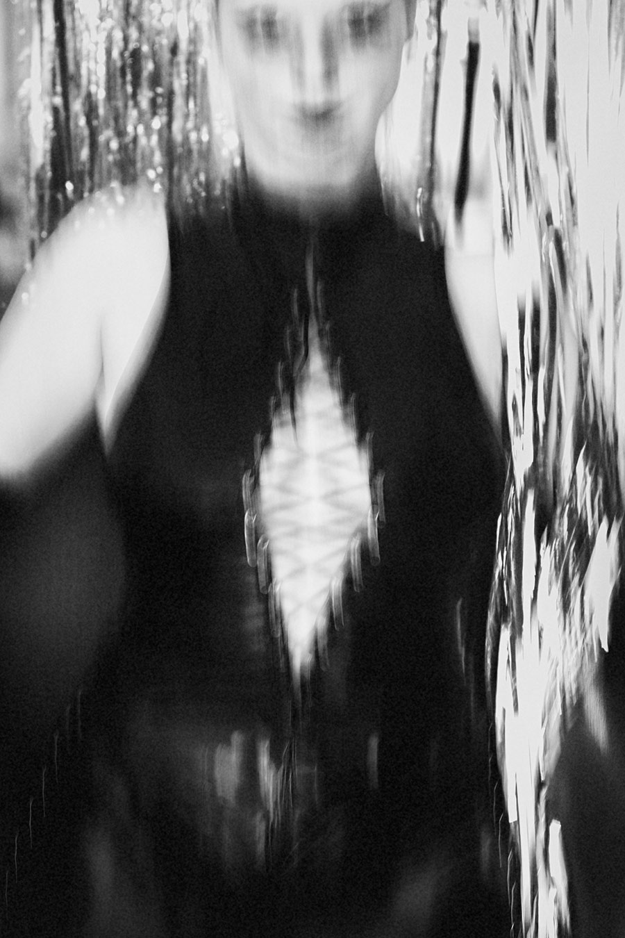 Frau im Latexanzug, um sie gewickelt ein Band mit der Aufschrift "Danger" fotografiert in schwarz/weiss