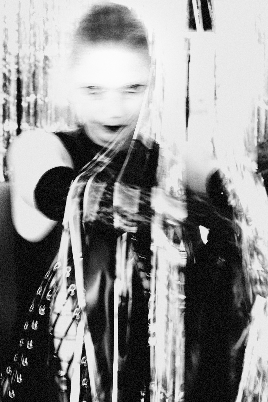 Frau im Latexanzug, um sie gewickelt ein Band mit der Aufschrift "Danger" fotografiert in schwarz/weiss