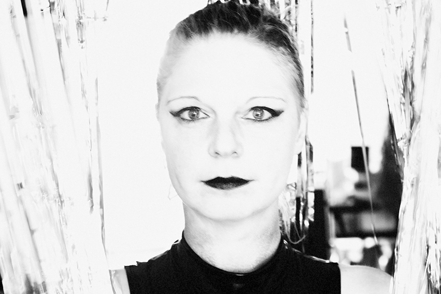 Frau im Latexanzug, um sie gewickelt ein Band mit der Aufschrift "Danger" fotografiert in schwarz/weiss