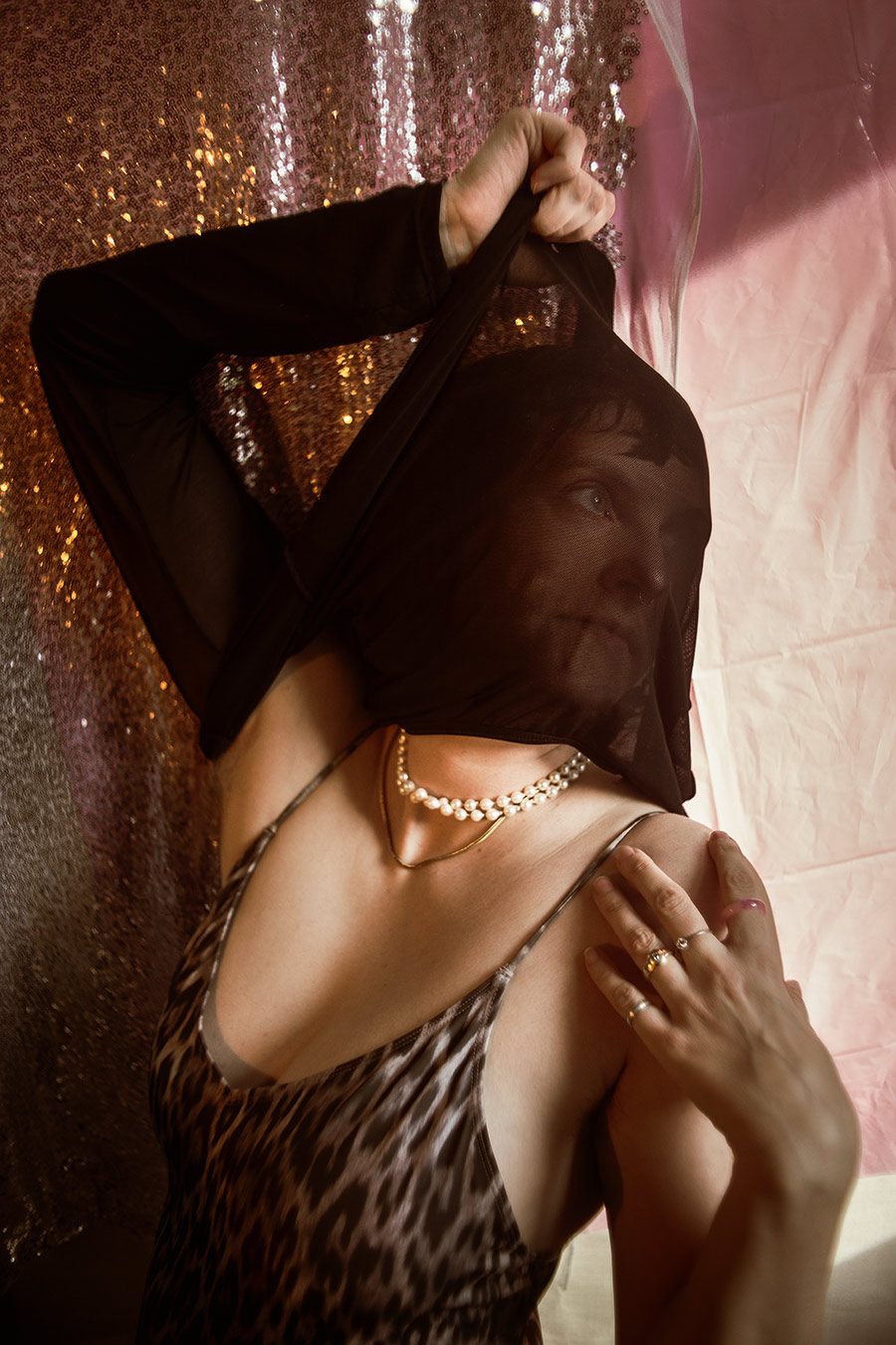 frau in einem leopardenbody und perlenkette, das gesicht ist verborgen