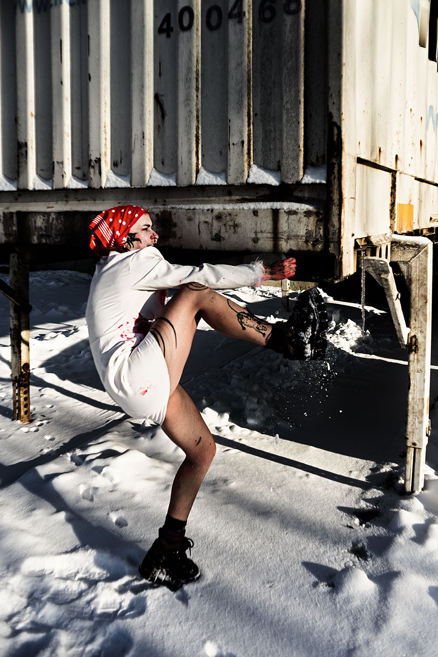 Person im Schnee mit fleckigem weißen Kleid und rotem Tuch