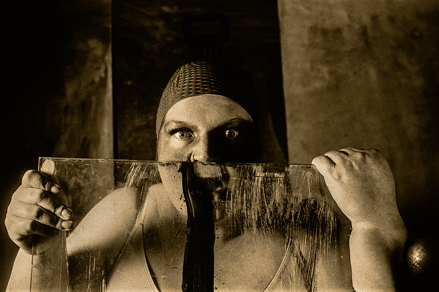 Frau hält Scheibe mit schwarzem Strich vor Gesicht, direkter Blick, Fomapan Ortho 400