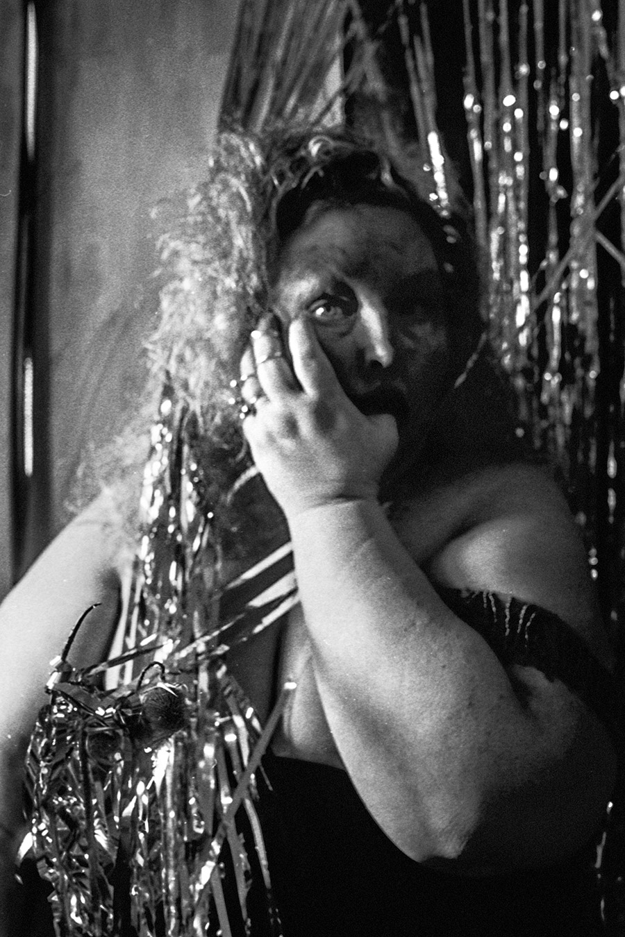 Analoges Selbstporträt mit Daumen im Mund vor Lametta, gepushter Film, Schwarz-Weiß