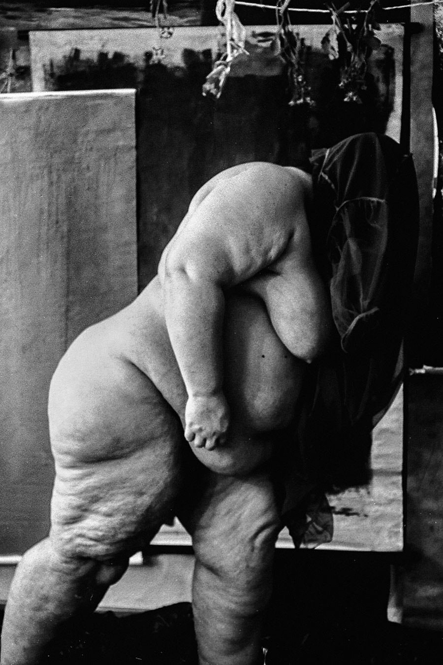 Nackter weiblicher Körper von hinten, gebückt, Hüfte und Oberschenkel füllen das Bild, getrocknete Blumen oben, analoges Schwarz-Weiß-Foto auf Kodak T-Max 100, Serie „Der Ballast"