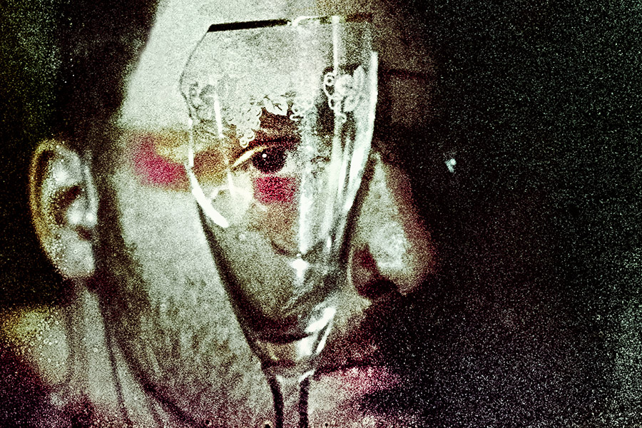 Analoges Porträt einer Person hinter einem Sektglas, Filmsuppe Fujicolor Superia 1600, Fotografin Leipzig