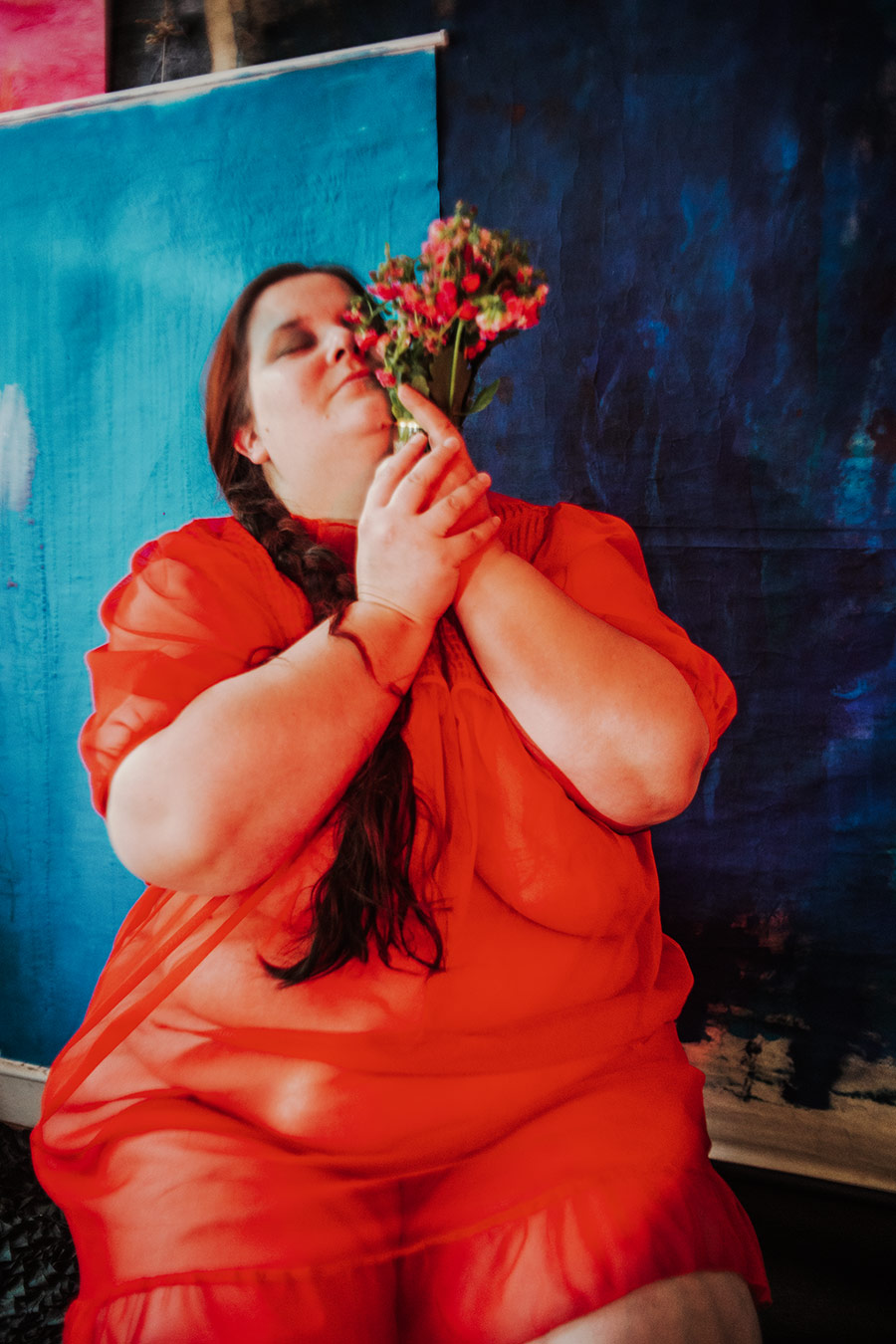 Frau in rotem Kleid mit geöffnetem Mund und zerfallenen Blumen in den Händen, blauer Hintergrund, Serie „Der Ballast"