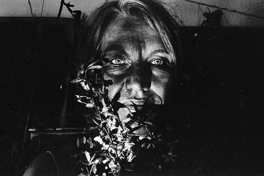 Greisenmädchen Teil 2, Nahporträt ältere Frau mit beiden offenen Augen hinter Blättern, Fomapan 400 Ortho, Fotografin Leipzig