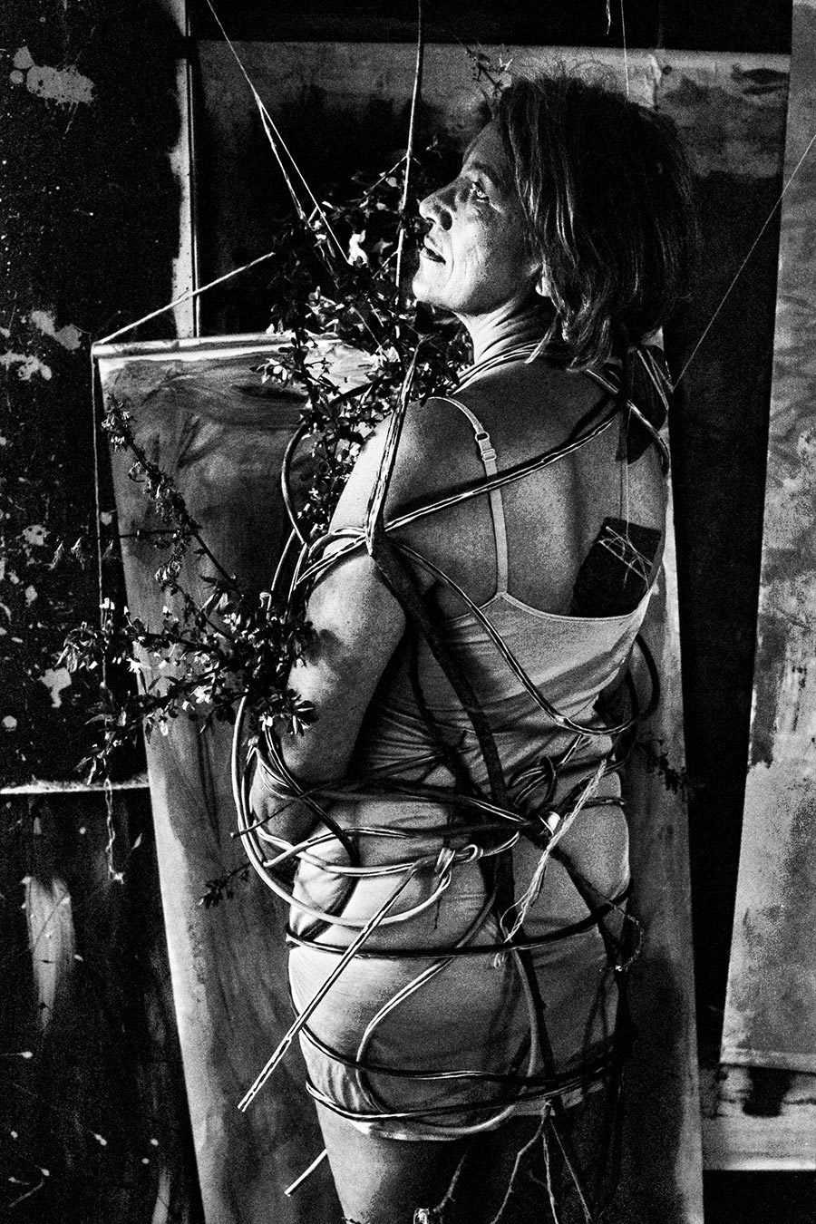 Greisenmädchen Teil 2, Frau schaut lächelnd nach oben, von Kabeln umwickelt mit Blütenzweigen, Fomapan 400 Ortho, Fotografin Leipzig