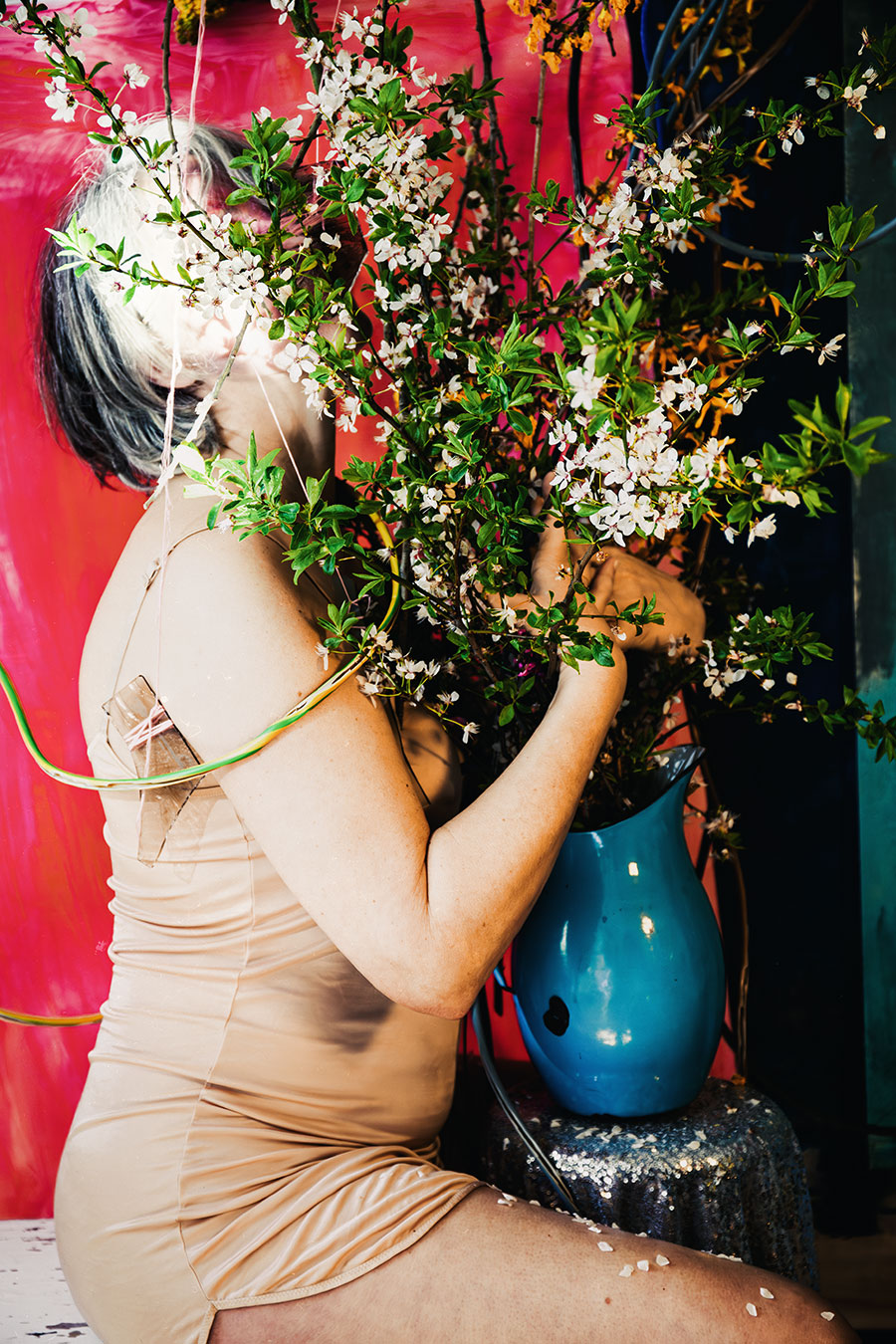 Fotokunst Greisenmädchen, Frau beugt sich zu blauer Emaillekanne mit weißen Blütenzweigen, Fotografin Leipzig