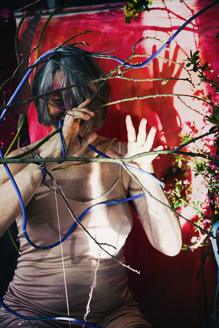 Fotokunst Greisenmädchen, Frauenkörper von Ästen und Kabeln durchzogen, Hand vor dem Gesicht, Fotografin Leipzig
