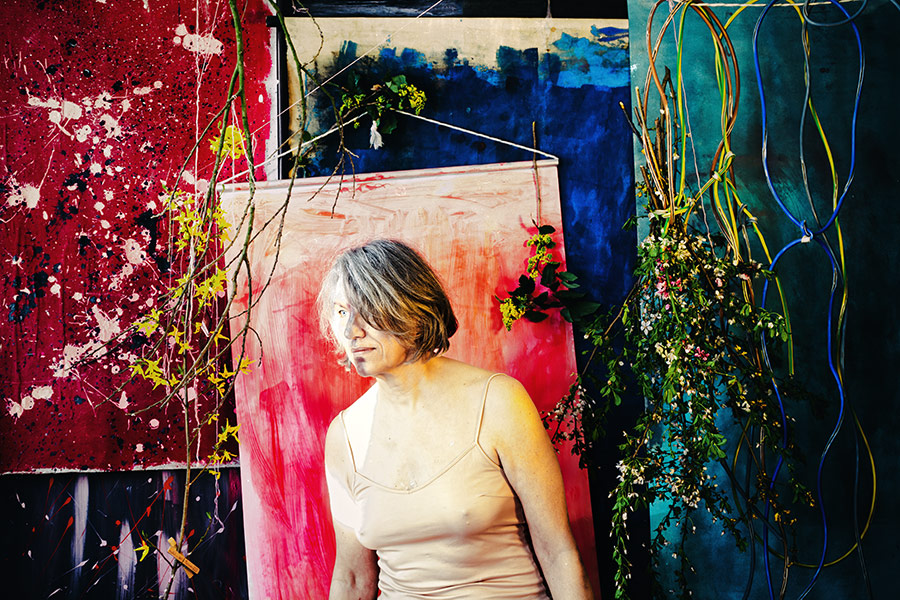 Fotokunst Greisenmädchen, Frau mit grauem Haar vor abstrakten Gemälden und hängenden Blütenzweigen, Fotografin Leipzig, Antje Kröger