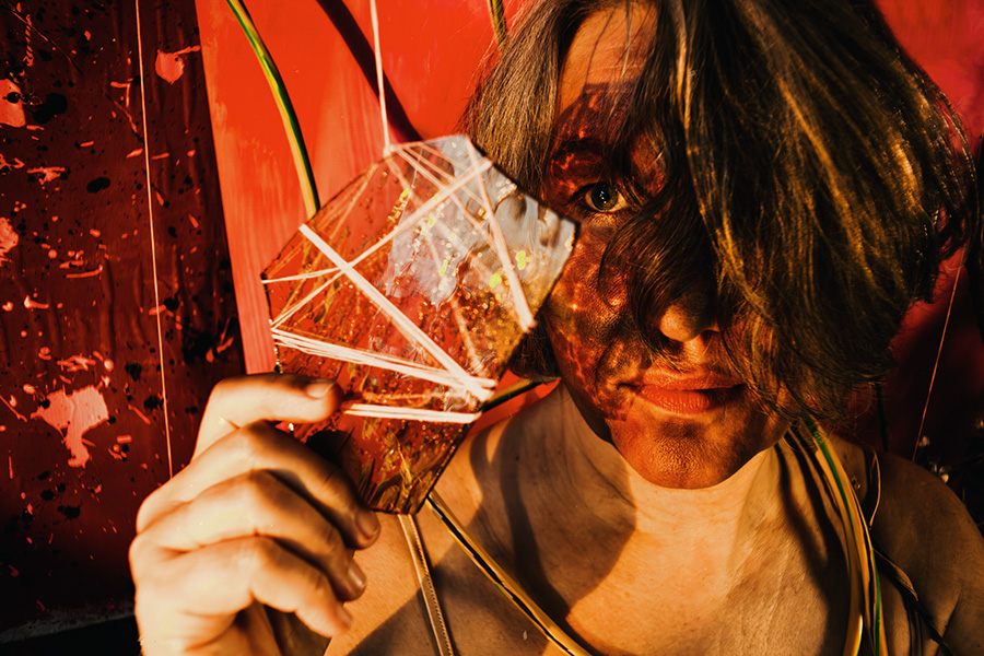 Fotokunst Greisenmädchen, Nahaufnahme bemaltes Gesicht hinter Glasscheibe in intensivem Rotlicht, Fotografin Leipzig