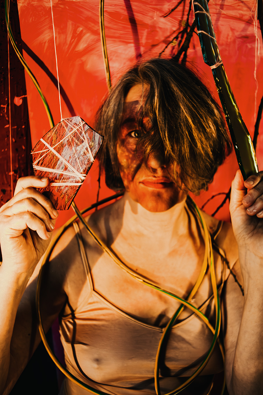 Fotokunst Greisenmädchen, Frau mit intensivem Blick hält Glasscheibe mit weißen Fäden im roten Licht, Fotografin Leipzig