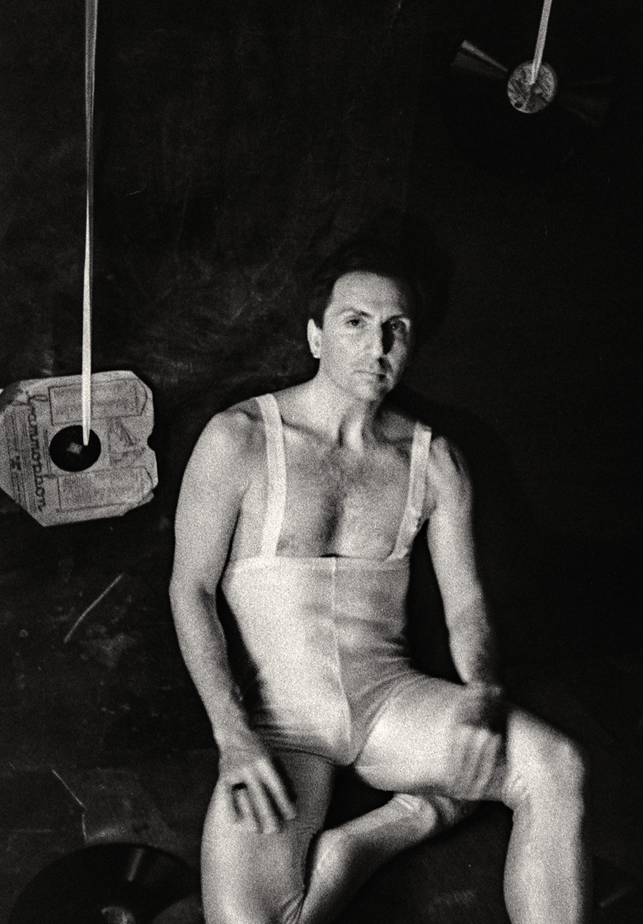 Fomapan 400 gepusht · Zenit, Schwarzweißfoto: Schwarzweißfoto: Nahaufnahme, Mann in weißem Trikot sitzt, direkter ruhiger Blick in die Kamera, Schallplatten im Hintergrund.