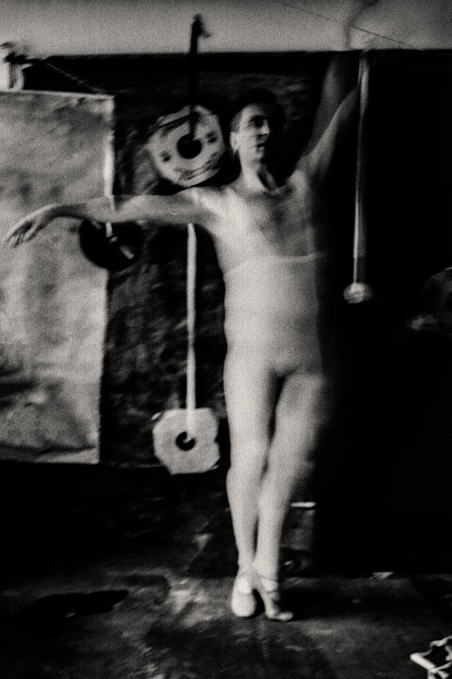 Fomapan 400 gepusht · Zenit, Schwarzweißfoto: Mann in weißem Trikot steht frontal, Arme leicht geöffnet, Spitzenschuhe, Schallplatten links und rechts, körniges Licht.