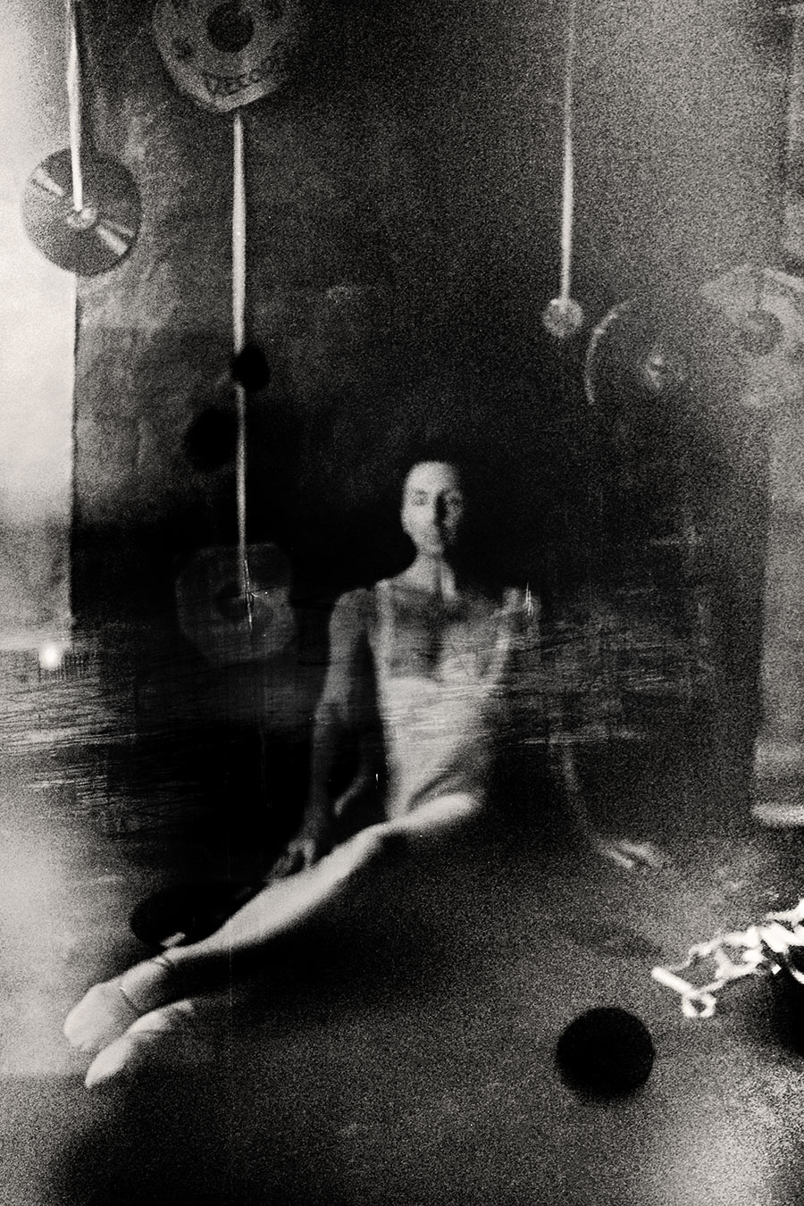 Fomapan 400 gepusht · Zenit, Sehr körniges analoges Schwarzweißfoto: Verschwommene sitzende Figur, fast geisterhaft aufgelöst, Schallplatten und Schnüre ringsum.