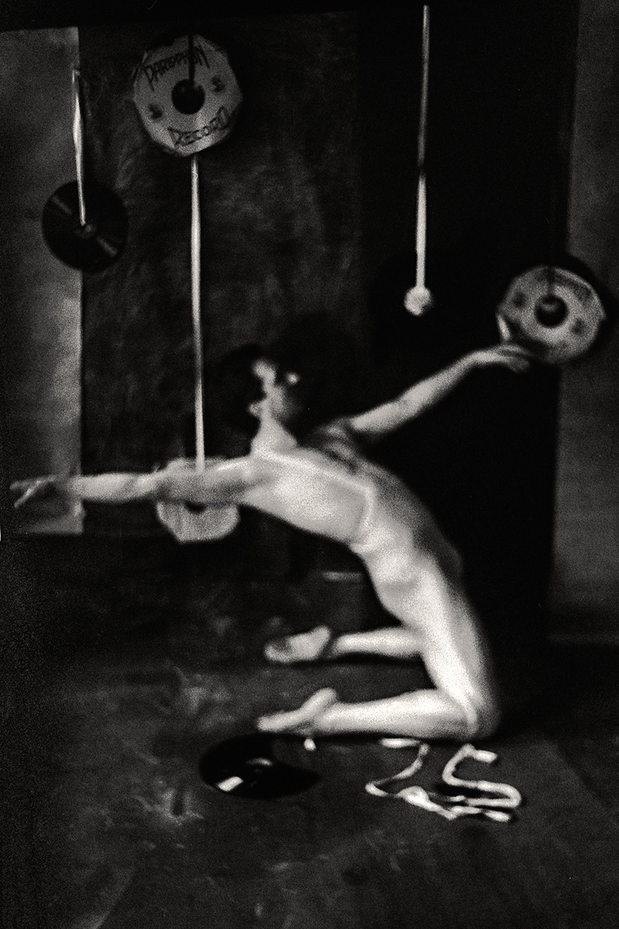 Fomapan 400 gepusht · Zenit, Stark gekörntes Schwarzweißfoto: Nackter Körper streckt einen Arm weit aus, fast abstrakte Form, sehr körnig und dunkel, analoge fotografie, Schallplatten im Hintergrund.