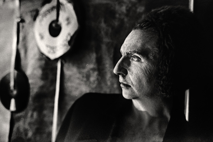 Tmax 100 auf 800 gepusht, analoge Fotografie Leipzig, Schwarzweißfoto: Nahaufnahme, Mann im Profil, Blick nach vorn in die Ferne, gealterte Haut, dunkler Hintergrund, Schallplatte unscharf links.