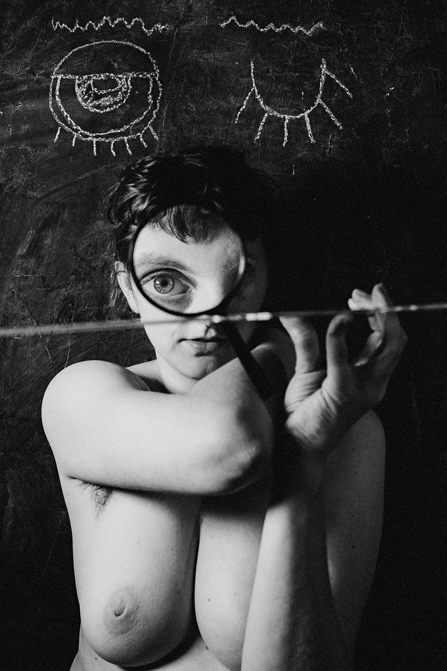 Trachom Fotokunst, Frau hält Lupe vor ein Auge und schaut direkt durch das Glas, Kreideaugen im Hintergrund, Fotografin Leipzig
