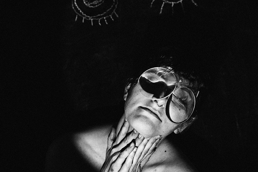 Trachom Fotokunst Nahporträt, Frau mit Lupe auf Gesicht, Hände am Hals, Kreideaugen im Hintergrund, Fotografin Leipzig