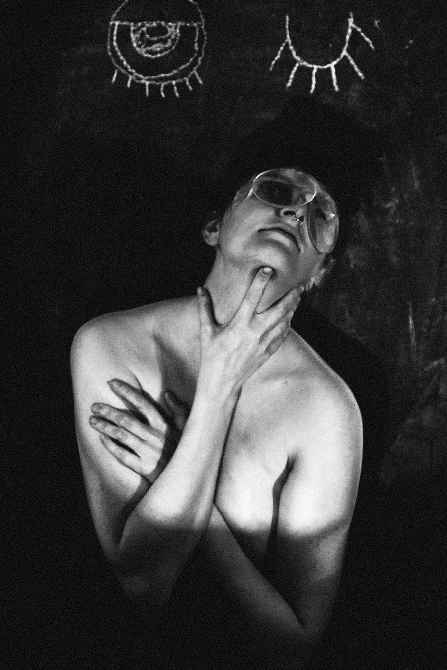 Trachom Fotokunst, Frau mit Lupe auf Stirn und überkreuzten Händen am Hals vor schwarzer Tafel, Fotografin Leipzig
