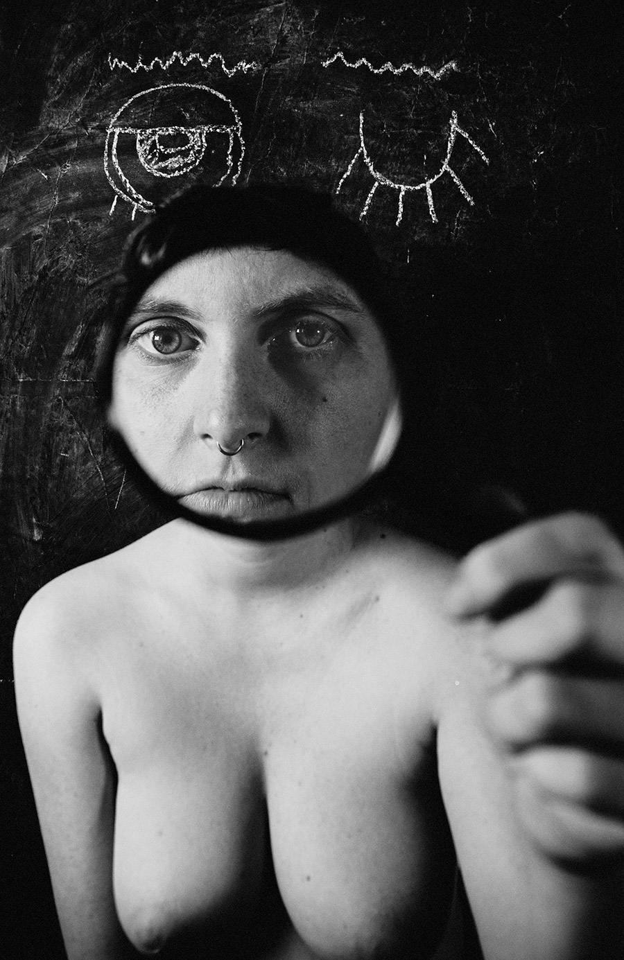 Trachom Fotokunst, frontales Nahporträt Frau mit Lupe die das Gesicht einrahmt und direktem Blick, Kreideaugen dahinter, Fotografin Leipzig
