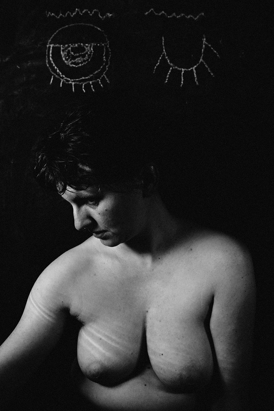 Trachom Fotokunst, Frau im Seitenprofil schaut nach unten ohne Lupe, Kreideaugen auf schwarzer Tafel oben, Fotografin Leipzig