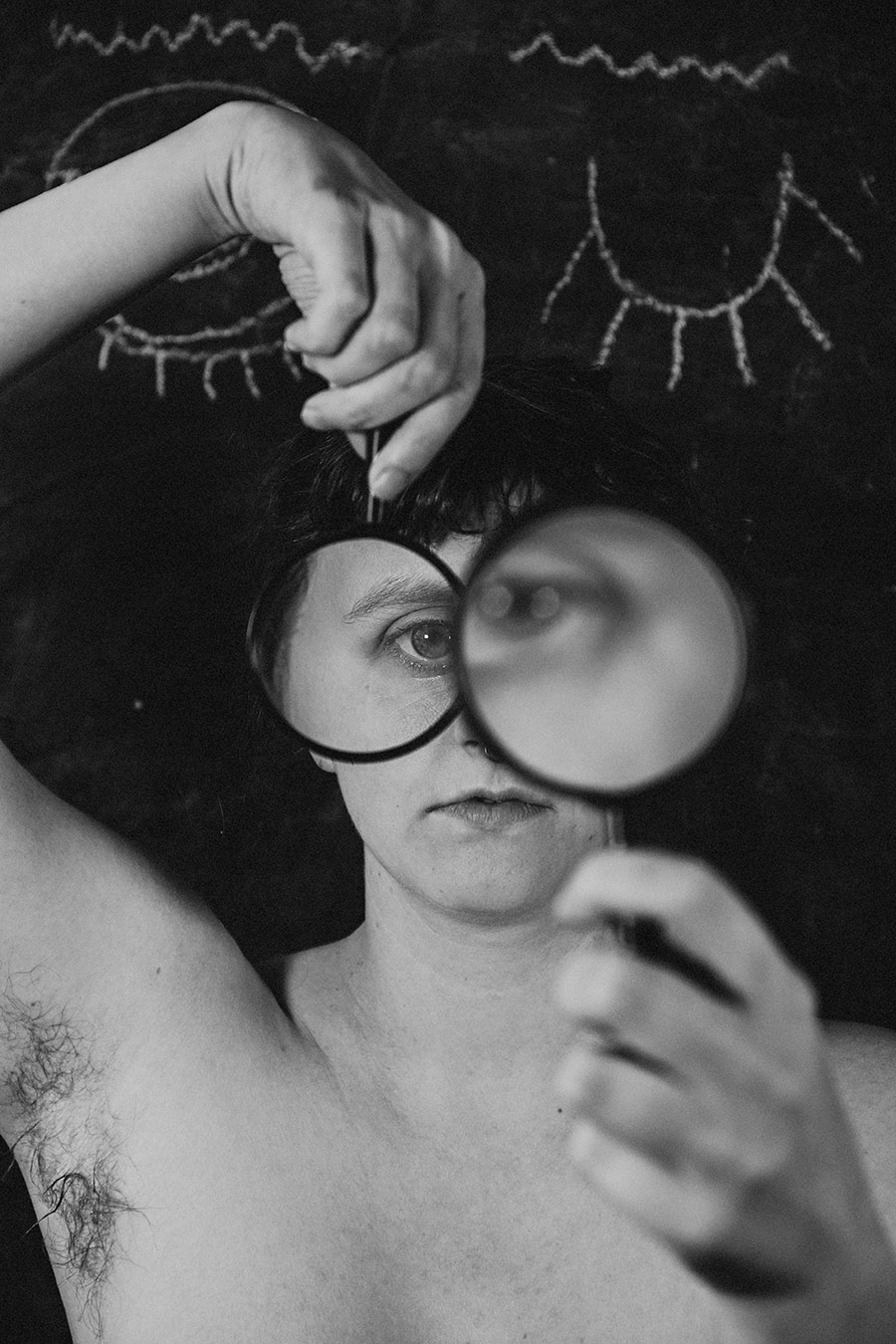 Trachom Fotokunst, Frau liegend mit zwei Lupen vor dem Gesicht vor Kreideaugen auf schwarzer Tafel, Fotografin Leipzig
