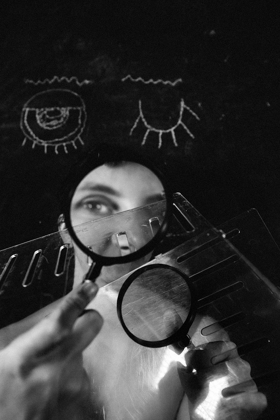 Trachom Fotokunst, Auge durch Lupe vergrößert hinter Metallschutzbrille vor Kreideaugen auf schwarzer Tafel, Fotografin Leipzig
