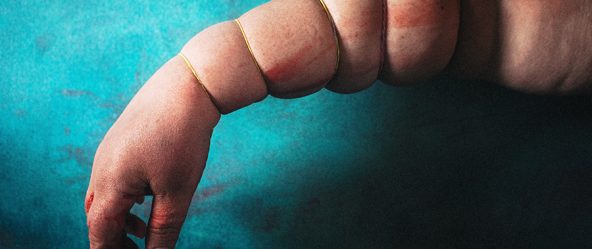 Arm senkrecht hängend, von Gummibändern gleichmäßig eingeschnürt, Haut quillt hervor, Hand schlaff und livide – inszenierte Körperfotografie Antje Kröger Berlin Leipzig, Serie Mehrenge