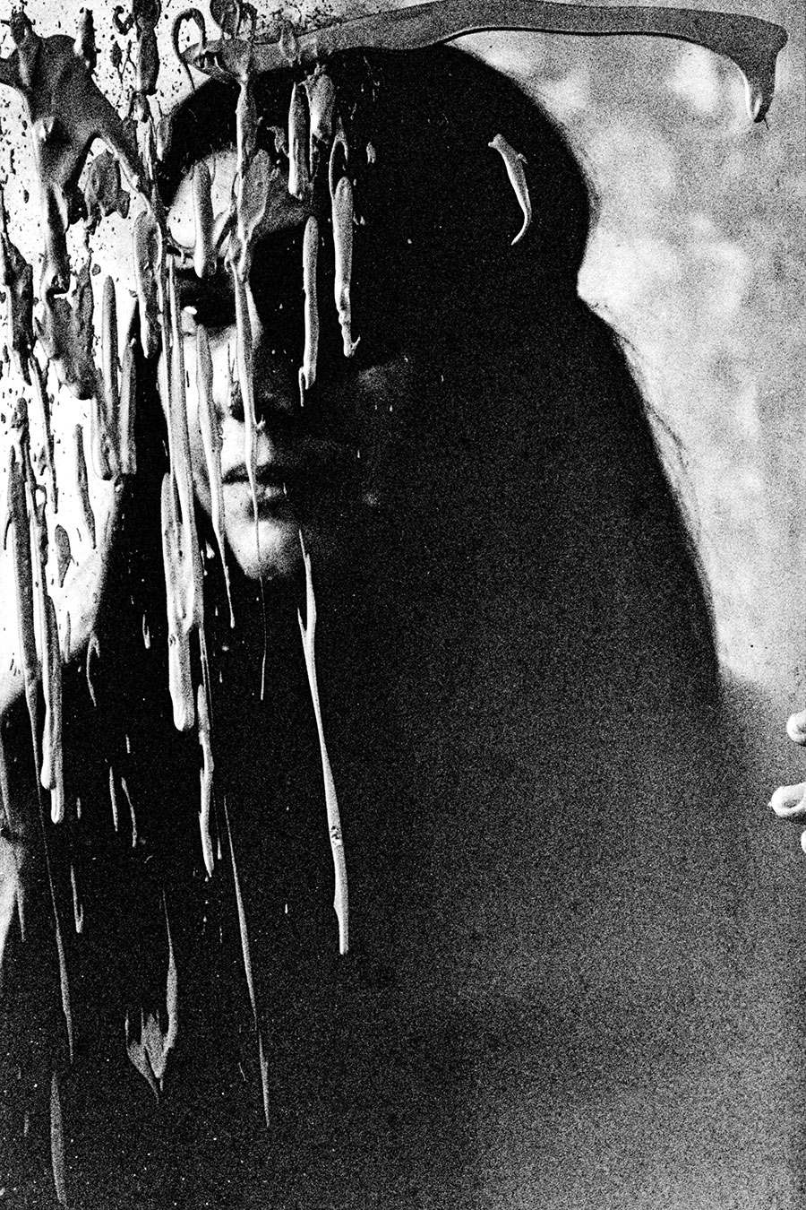 Analoge Aktfotografie Schwarz-Weiß, Nahaufnahme Gesicht einer Frau mit langen dunklen Haaren, das Gesicht halb verdeckt von herabhängenden Farbstreifen und Tropfen eines bespritzten Gemäldes, extrem körnig, dramatische Beleuchtung, Fotokunst.