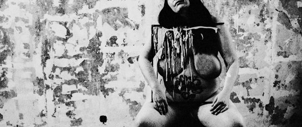 Analoge Aktfotografie Schwarz-Weiß, dicke Frau mit schwarzer Augenklappe sitzt nackt auf Stuhl, Kopf zurückgelehnt, vor dem Körper ein mit weißer Farbe bespritztes Gemälde, stark verwitterte Wand, Weitwinkelaufnahme, körnige Filmfotografie, Fotokunst.