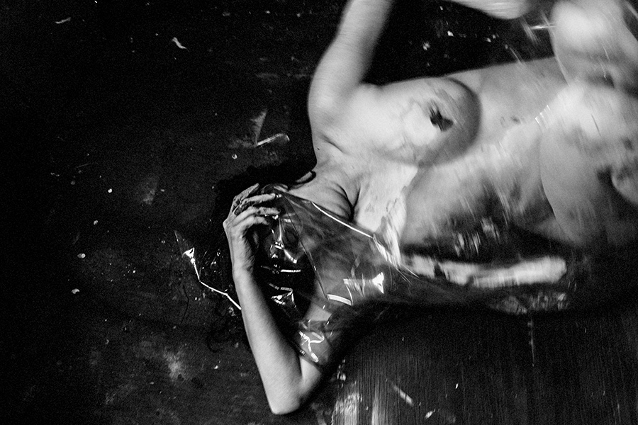 Bewegungsunschärfe – liegender Körper greift nach Folie, Haut und Material verschwimmen ineinander.