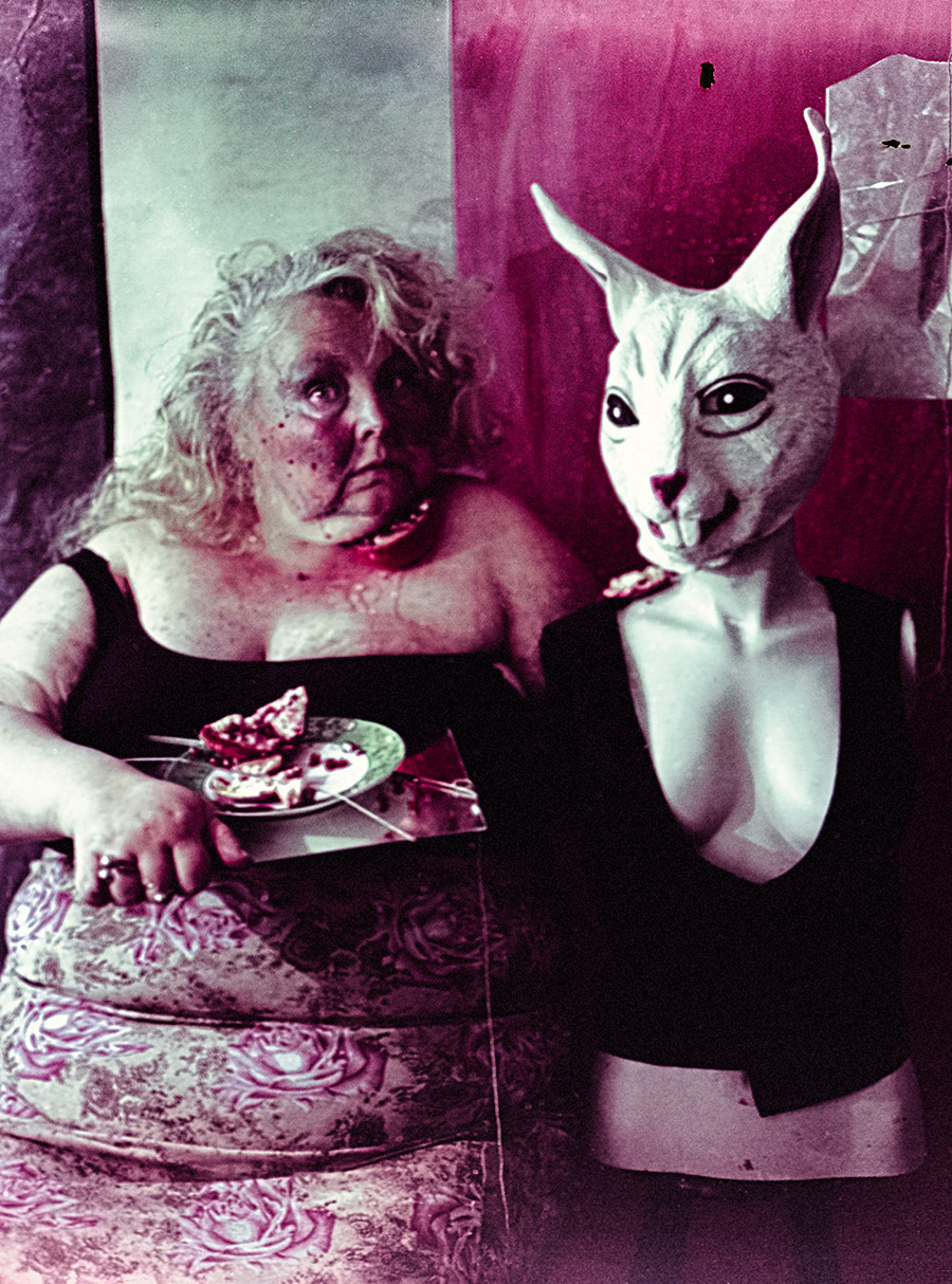 Selbstporträt mit Häschenmaske am gedeckten Tisch, Granatapfel auf Teller mit Besteck, Filmsuppe-Farbverschiebung in Grün-Magenta auf Kodak Color 200 — Fotokunst Antje Kröger Berlin Leipzig, Serie Tischgesellschaft