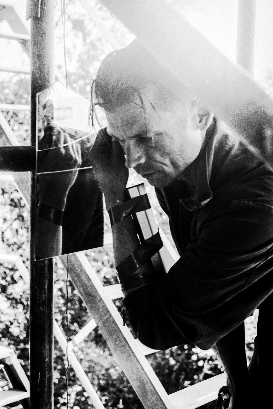 Zenith analog, inszenierte Fotografie, Mann beugt sich zu Spiegelreflexion, Kamera spiegelt sich, hartes Licht, gepushter Film, Schwarzweiß, Meta-Fotografie