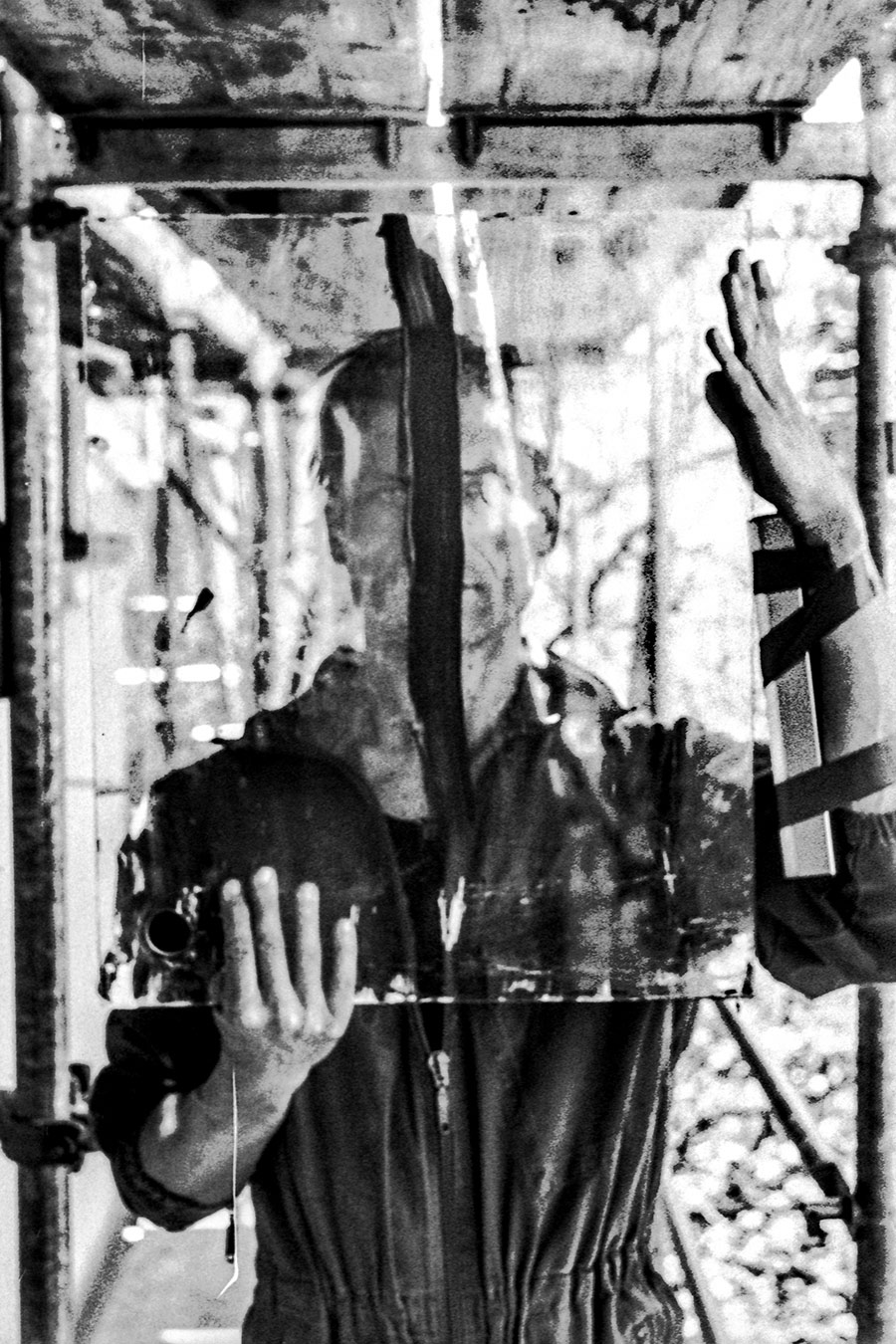 Zenith analog, inszeniertes Schwarzweißfoto, Mann hält großes Spiegelstück vor Gesicht, hartes Licht, Kamera in Reflexion sichtbar, gepushter Film, konzeptuelle Fotografie