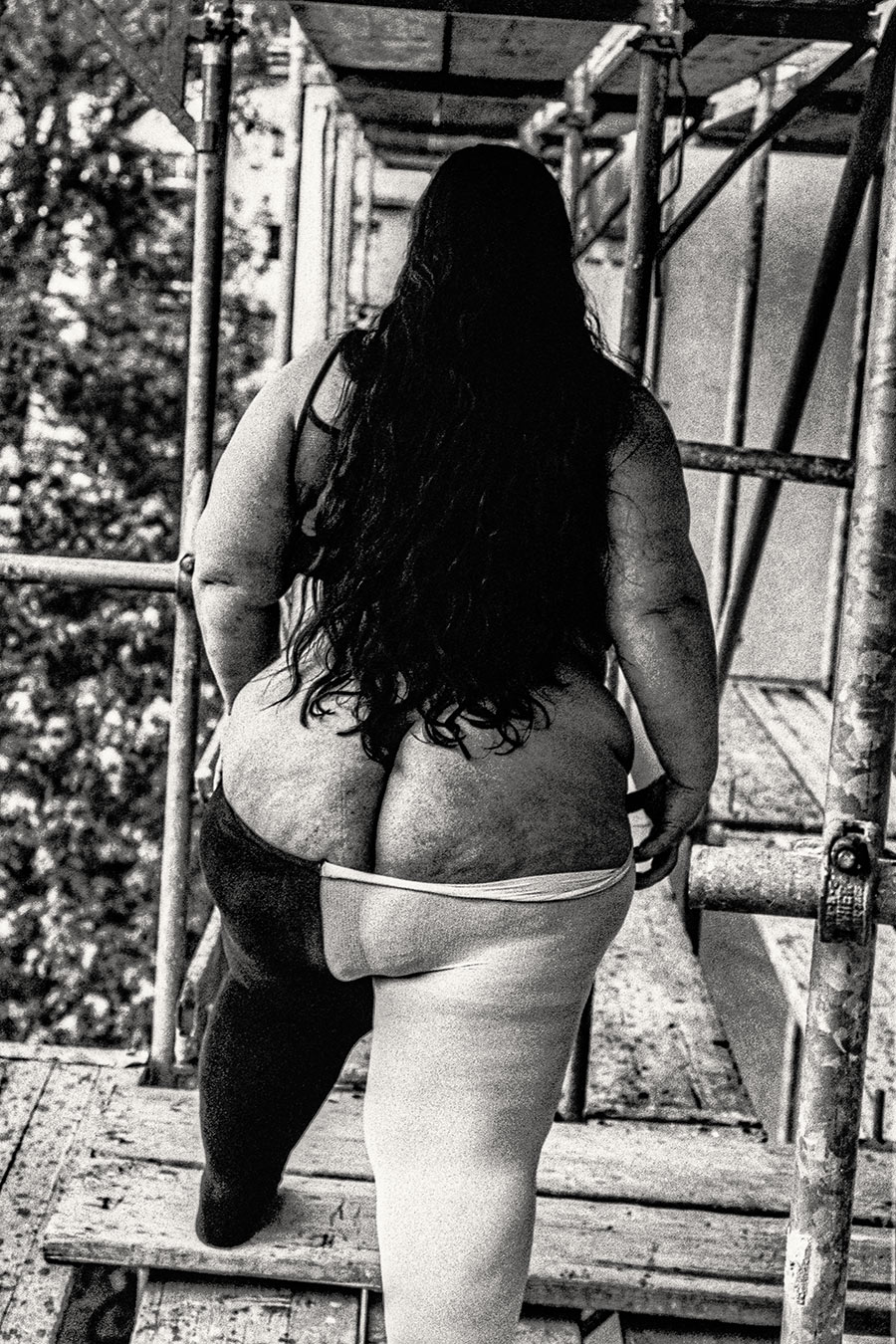 Dicker weiblicher Körper von hinten auf Gerüst stehend, langes Haar, Sommerlaub, analoges 35mm-Schwarzweiß – Antje Kröger Fotokunst Leipzig Berlin, Serie Walsturz