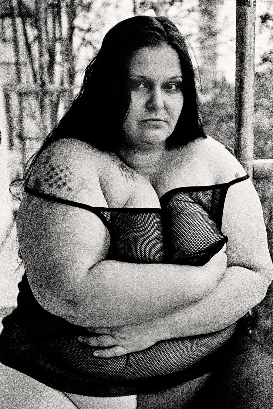 Frontalporträt mit verschränkten Armen, harter direkter Blick, Netz-Oberteil, dicker Körper, dramatisches 35mm-Schwarzweiß – Antje Kröger Fotokunst Leipzig Berlin, Serie Walsturz