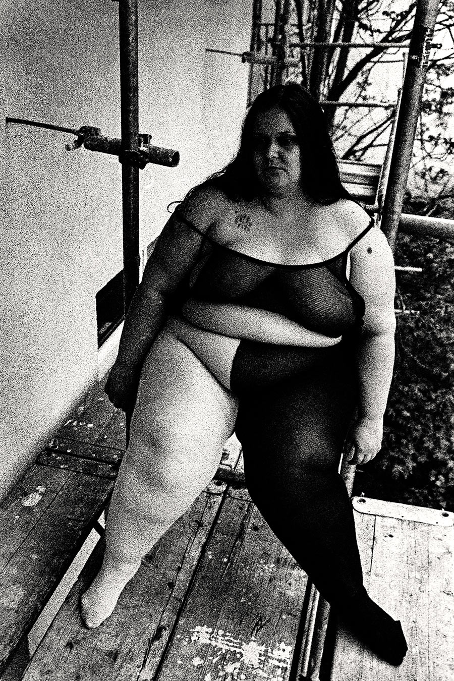 Dicke Frau sitzend auf Gerüst, Bäume, körniges 35mm-Schwarzweiß, inszenierte Körperfotografie – Antje Kröger Leipzig, Serie Walsturz