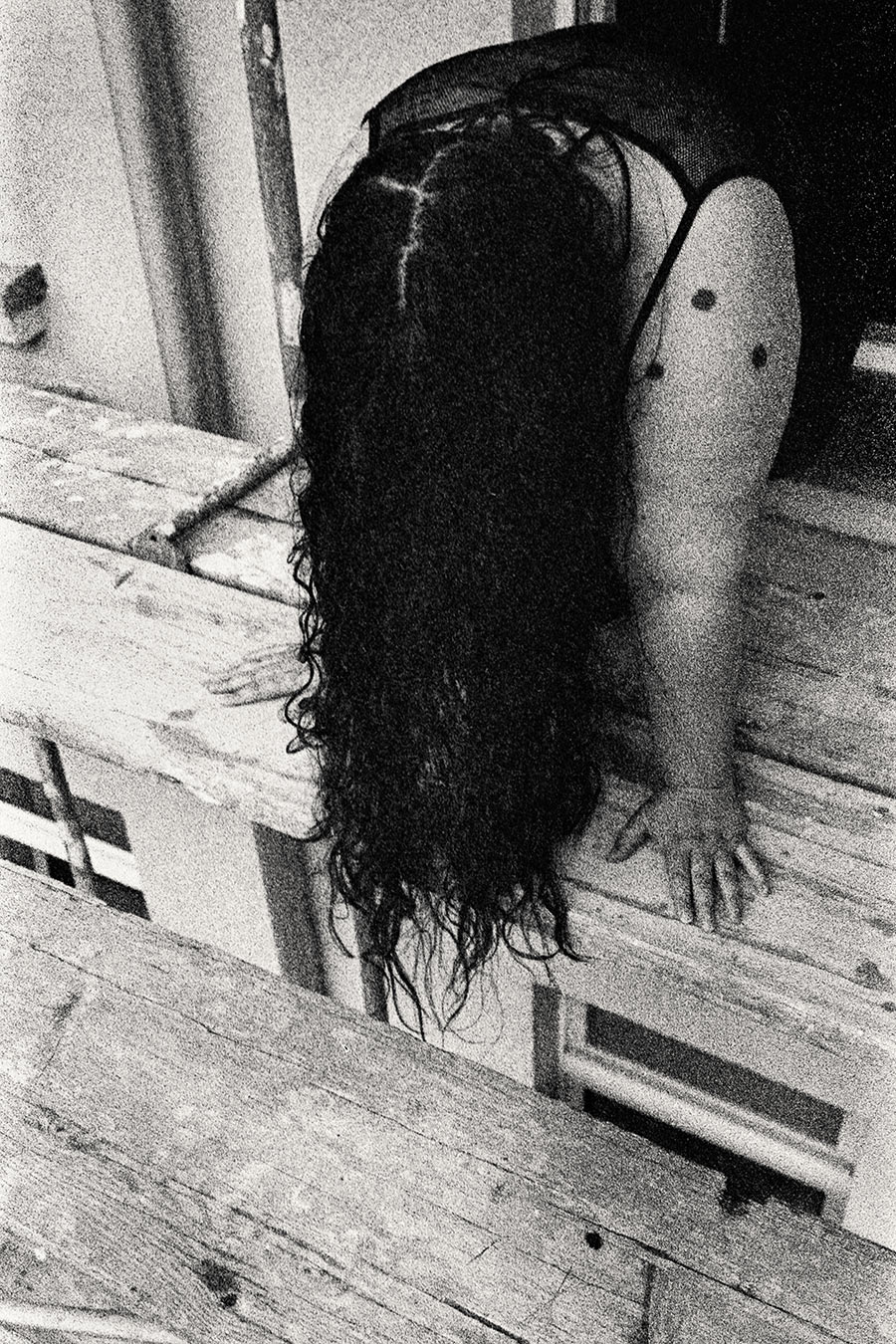 Kniende Frau auf Gerüst, Haar fällt komplett nach vorne, dicker Rücken zur Kamera, körniges 35mm-Schwarzweiß – Antje Kröger Fotografie Leipzig, Serie Walsturz
