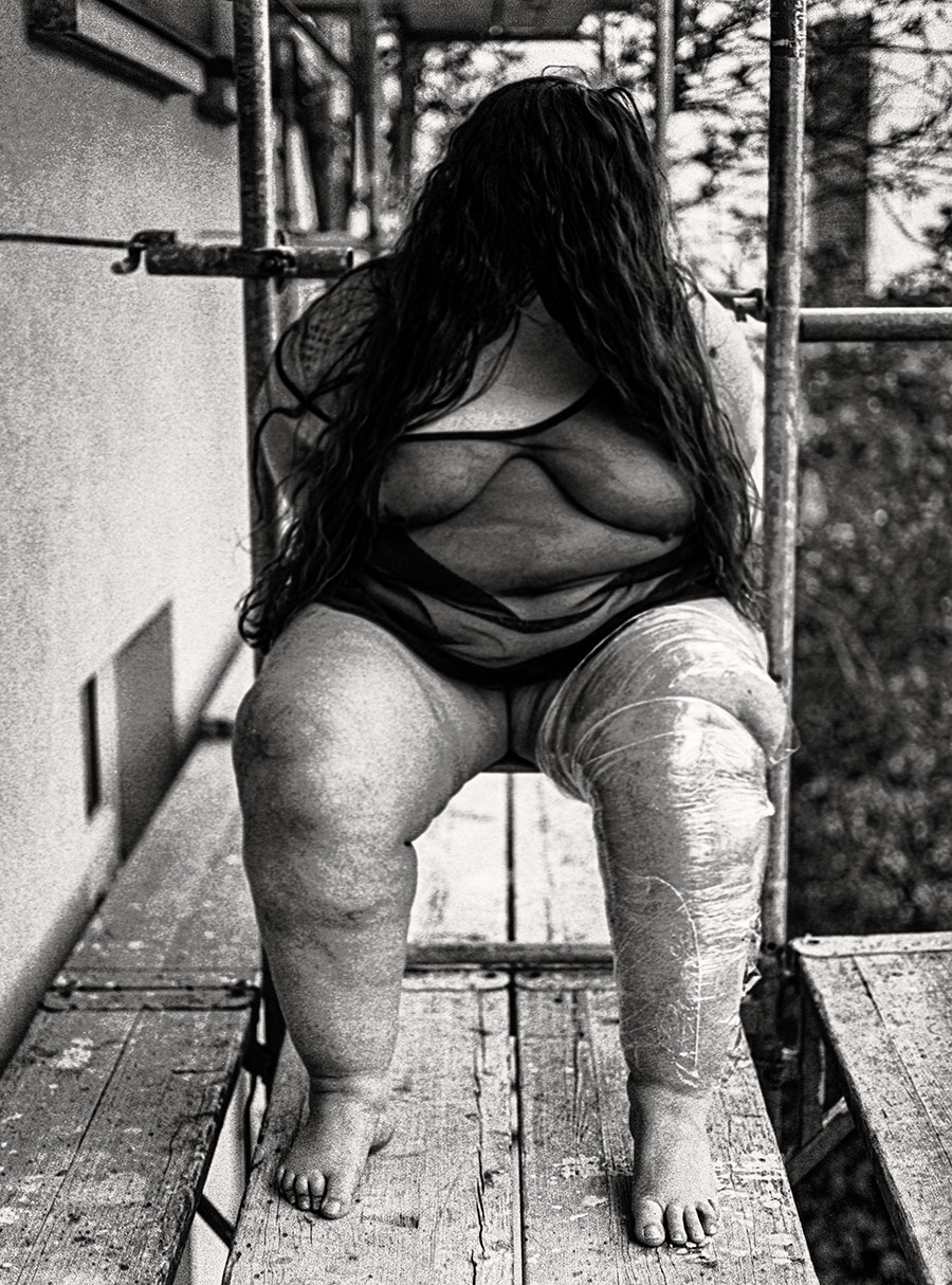 Analoge Fotografie, Mamiya, 120mm, dicke Frau auf Gerüst, ein Bein ist in Klarsichtfolie eingewickelt