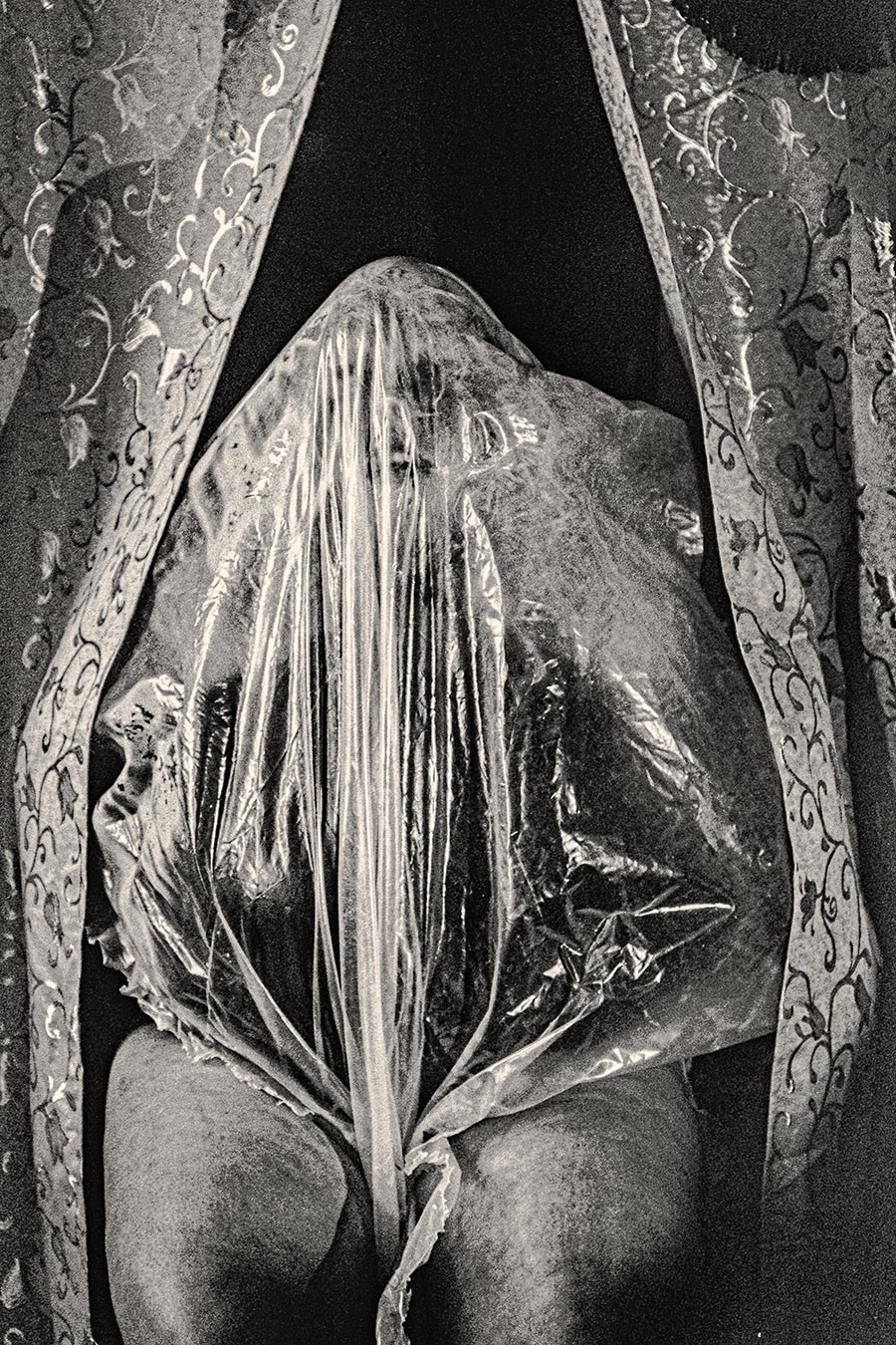 Transparente Folie hängt vertikal über Kopf und Oberkörper einer Person wie ein Schleier, analoges Schwarzweißfoto