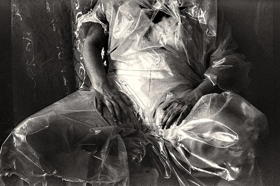 usschnitt von Schoß und Händen unter transparenter Folie, kein Gesicht sichtbar, fast abstrakte Schwarzweißfotografie Fomapan Ortho 400