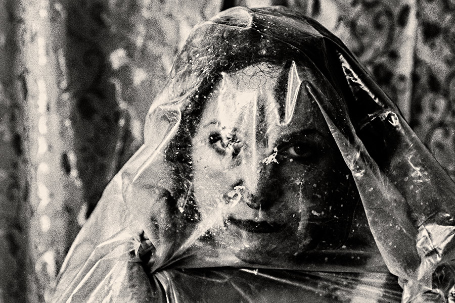 Extremnahaufnahme eines Gesichts hinter verkratzter transparenter Folie, direkter Blick, analoges Schwarzweißfoto Fomapan Ortho 400