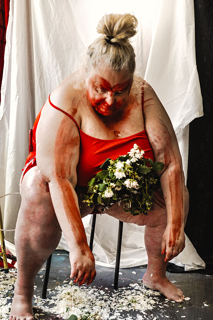 Fotokunst dicke Frau roter Body nach vorne gebeugt Blumen Schoß rote Farbe Körperkunst