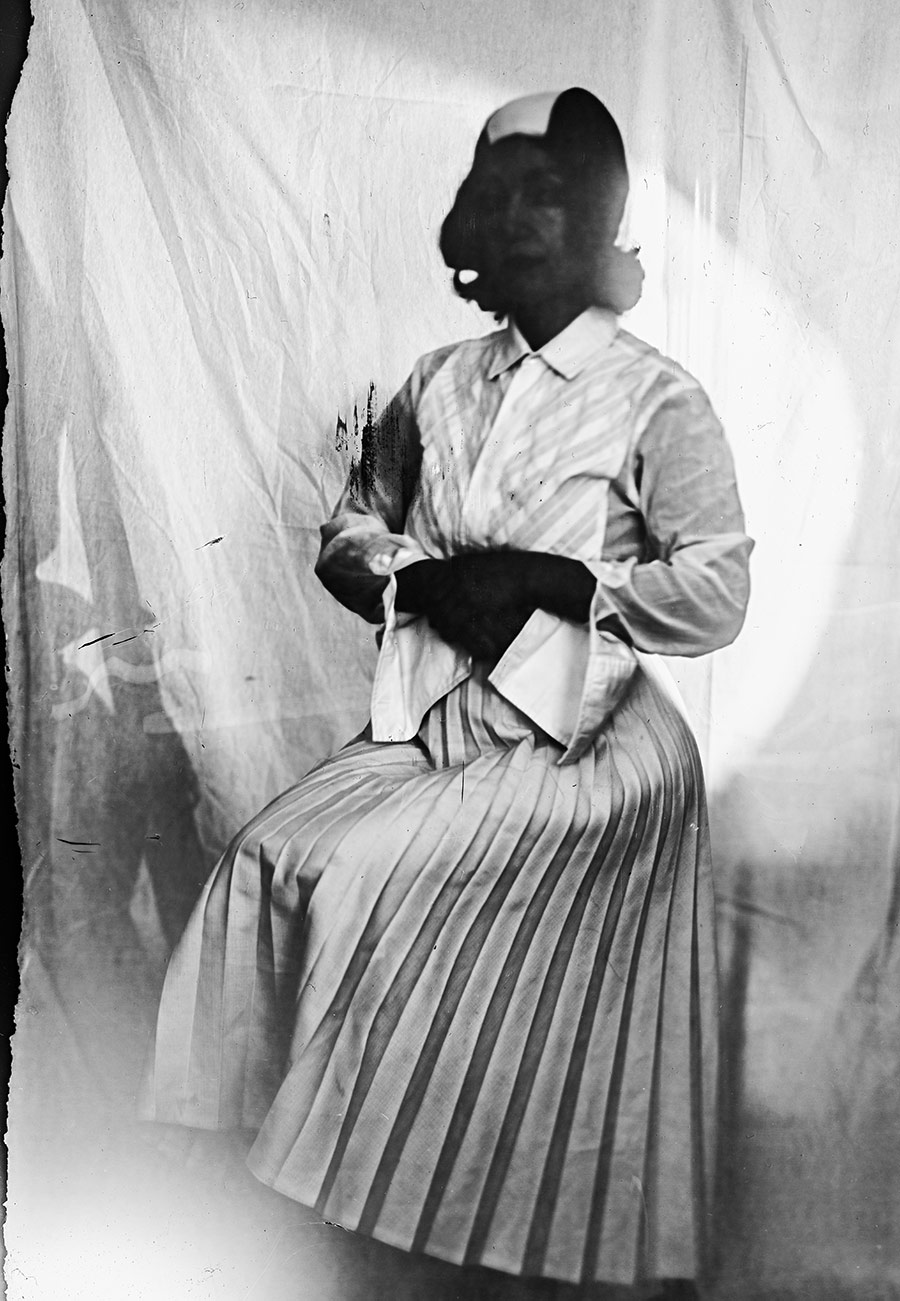 Analoges Portrait auf Fotopapier ORWO, sitzende Frau in Bluse und Faltenrock, Kopf geschwärzt, Hände verschränkt, Kamera Mentor, Serie Meeresschnee, Antje Kröger