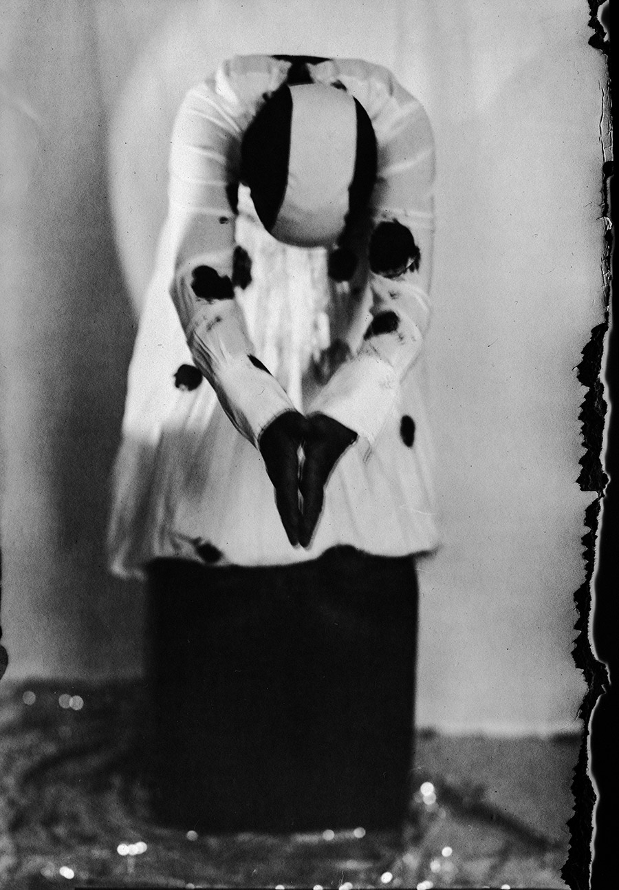 Analoges Portrait auf Fotopapier ORWO, Körper nach vorn gebeugt, Kopf im Dunkel verschwunden, gepunktete Bluse und Rock, Glitzer am Boden, Großformatkamera Mentor, Serie Meeresschnee Teil 2, Antje Kröger