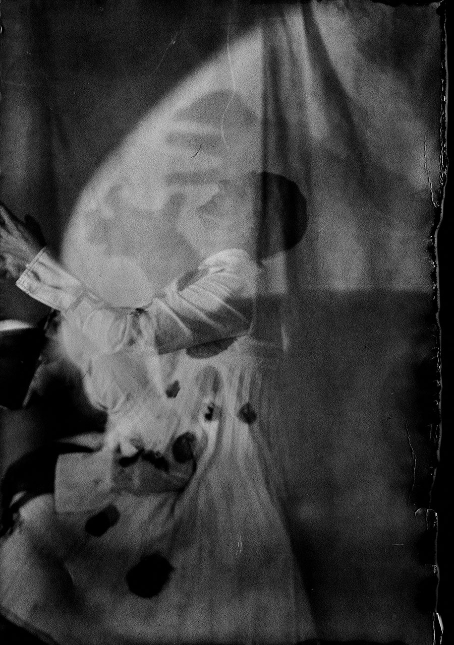 Analoges Portrait auf Fotopapier ORWO, Körper fast aufgelöst in Dunkelheit, gepunkteter Rock und Bluse, gerissene Papierränder, Großformatkamera Mentor, Serie Meeresschnee Teil 2, Antje Kröger