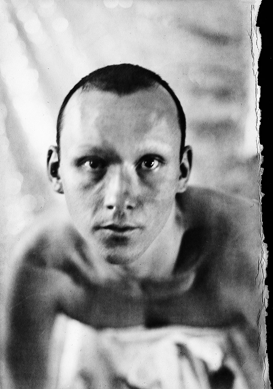 Direktes Porträt, Blick in die Kamera, verschränkte Arme im Unscharfen, Kamera Mentor Schwarzweißaufnahme, ORWO Fotopapier, analoge Fotografie Meeresschnee 3